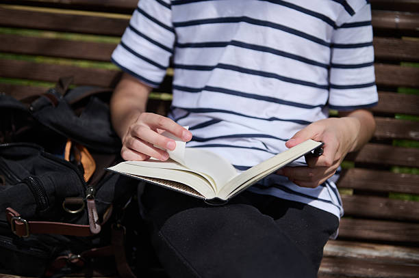 istock Person Reading a Book Outdoors on a Bench, Wearing Casual Attire 2220309343