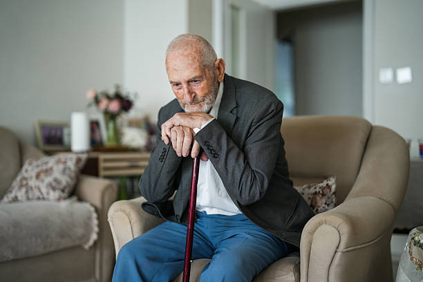 istock Lonely Elderly Man Sitting Thoughtfully at Home with Walking Cane 2220311635