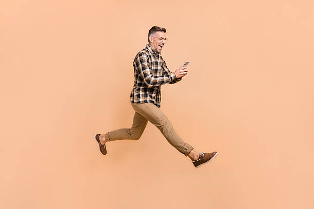 istock Full size profile side photo of excited man type sms cellphone jump step run comment post hurry isolated over beige color background 2220313222
