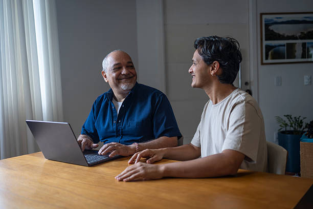 istock Father using laptop with Latino son in living room 2220313953