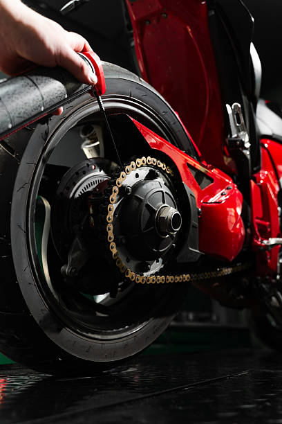 istock Motorcycle Chain Lubrication with Oil. Oiling motorcycle chain helps reduce wear, prevent rust, and ensure clean drivetrain for top riding performance. Clean oil spray is applied to motorcycle chain. 2220314235