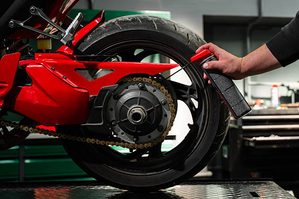 istock Motorcycle Chain Lubrication with Oil. Oiling motorcycle chain helps reduce wear, prevent rust, and ensure clean drivetrain for top riding performance. Clean oil spray is applied to motorcycle chain. 2220314247