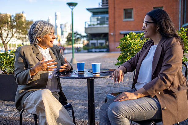 istock Two professionals conversing outdoors in an urban business setting. They are have a coffee break 2220320179