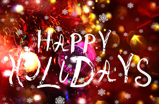 Happy Holidays saying, handwritten text. New Year decorations. Christmas Tree with baubles and shiny flare lights, bright festive background