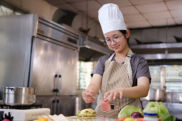 istock Chef adding ham slice to a fresh sandwich in a commercial kitchen. 2220336532