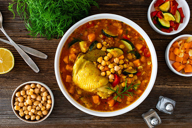 Fresh vegetable soup with lentil, chickpea and chicken on wooden table
