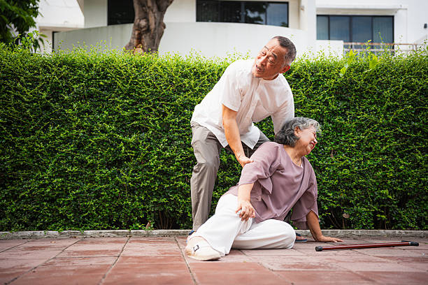istock Senior Man Helping Fallen Woman Outdoors, Concerned Husband Assistant Wife Who Has Fallen on Pavement, Elderly Asian Couple Facing a Medical Emergency Outside Their Home 2220338438