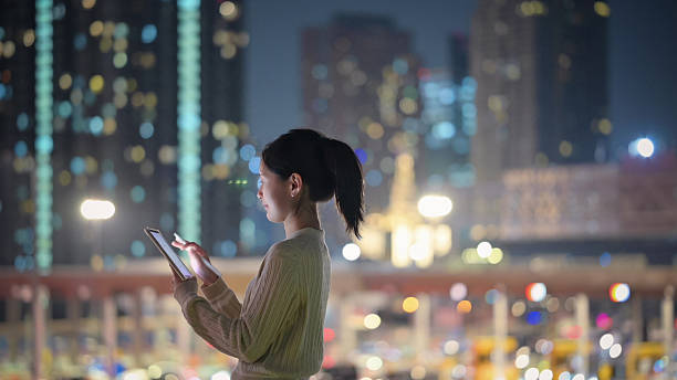 istock gen z female using smart device outdoors at night in modern urban technology environment  representing digital connection outdoors at night 2220344021