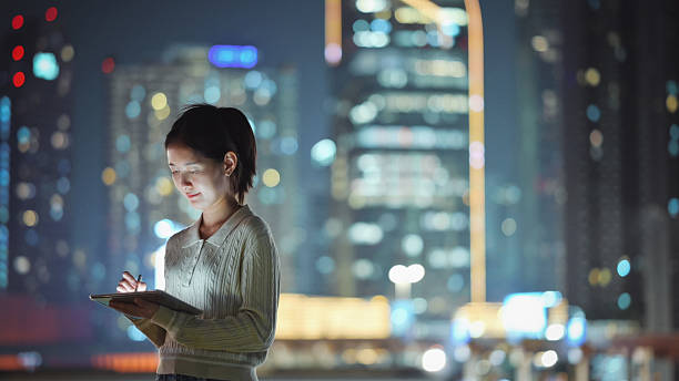 istock female entrepreneur gen z woman using smart device working on digital tablet at night with illuminated city skyline in downtown city for fintech and digital business 2220344024