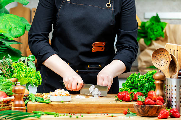 istock Chef cuts shallots onion prepare gourmet salad. Cozy kitchen with wooden table, kitchenware, vegetables, herbs and ingredients for cooking. Healthy vegan food, eating, recipes, blogging 2220361672