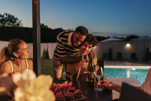 istock Friends embracing and enjoying dinner by the pool during summer vacation 2220363965