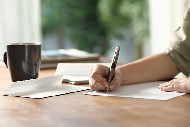 Woman hands handwriting letter on paper at home stock photo