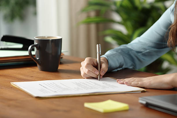 istock Office worker hands signing a paper contract on wooden table 2220369543