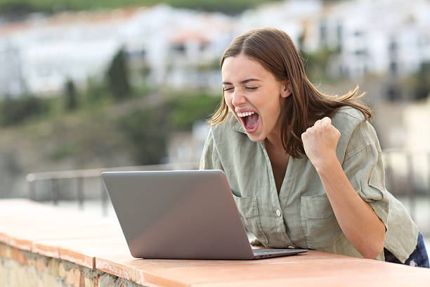 istock Excited woman celebrating checking laptop on vacation 2220369845