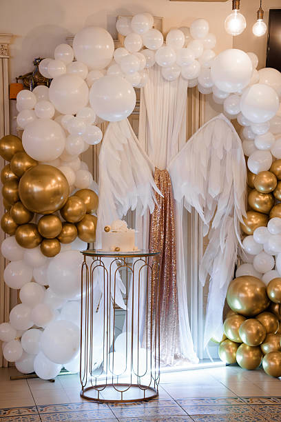 istock Elegant White and Gold Balloon Arch Backdrop with Cake Table for Celebrations, Parties, Weddings, Luxury Events, and Angel Wings Theme 2220370006