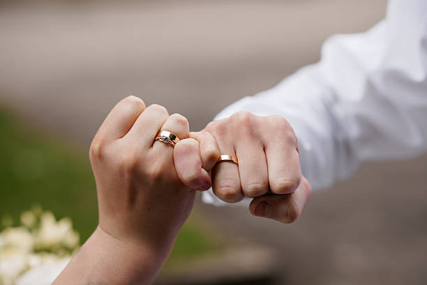 istock Romantic Wedding Rings Exchange: Close-up of Hands with Gold Bands Symbolizing Love, Commitment, and Marriage During Outdoor Celebration. 2220372286