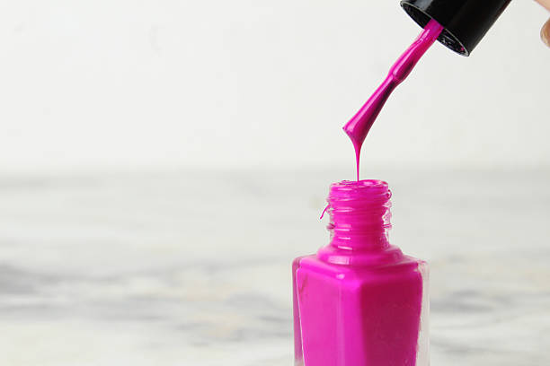 Nail polish drips, drips from the brush into the bottle on a white light background, there is a place for copyspace text. Hand Care.