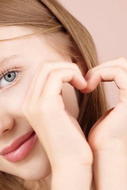 istock A smiliing girl forms a heart shape hands. Self care ads. Face. Love Support 2220379988