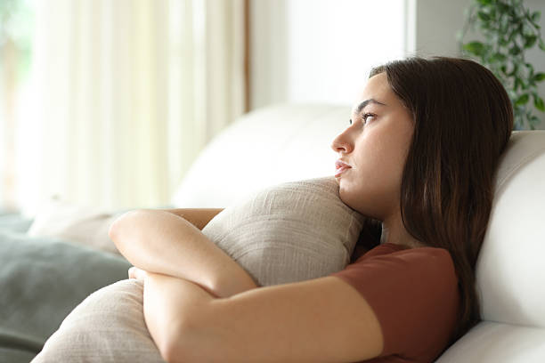 istock Apathetic woman hugging pillow on a sofa at home 2220381617