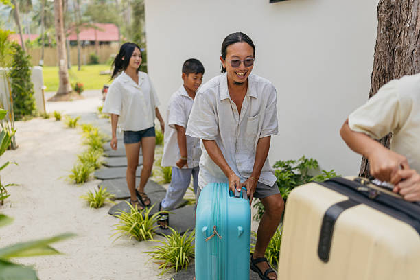 istock Asian family arriving at tropical resort pulling suitcases 2220382401