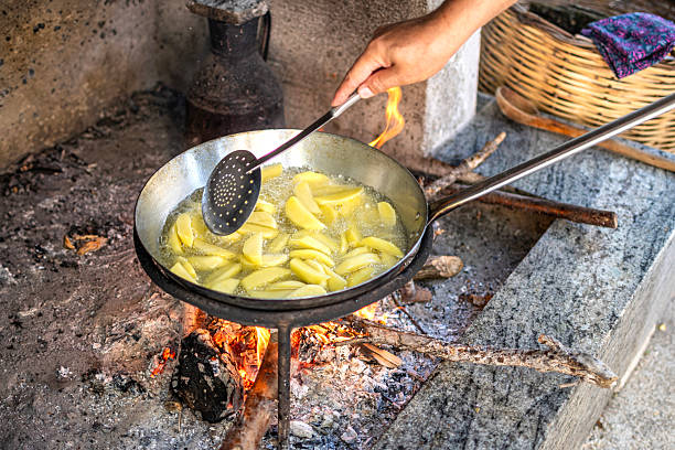 Potatoes are cooked in a large pot on fire. Food is cooked on a campfire in marching conditions