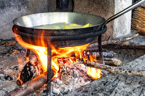 Potatoes are cooked in a large pot on fire. Food is cooked on a campfire in marching conditions