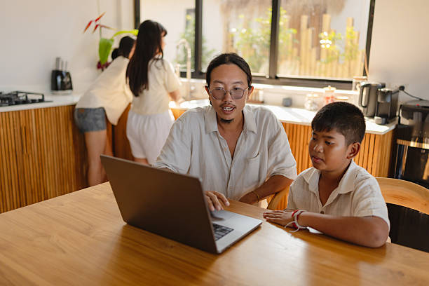 istock Father helping son with homework on laptop 2220383297