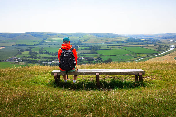 istock Hiker sitting on bench looking at view on South Downs in southeast England 2220385592