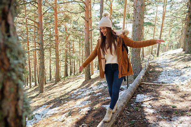 istock Young woman balancing on a log while hiking in a snowy forest 2220385905