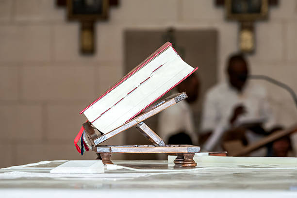 A Catholic missal or lectionary placed on a wooden altar stand during a religious ceremony. Used for readings and prayers in a baptism or communion mass inside the church.