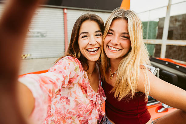 istock Two young women taking a selfie while leaning on their red convertible car 2220391202