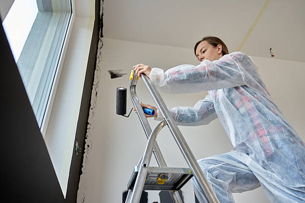 Young happy woman paints her apartment