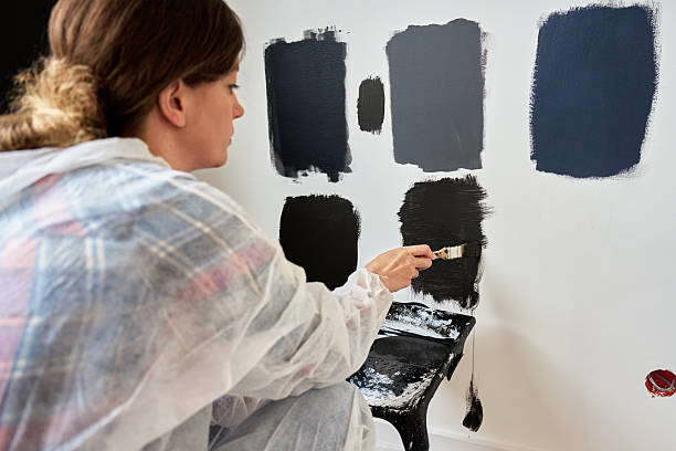 istock Woman Testing Black Paint Samples on Wall During Apartment Renovation 2220392587