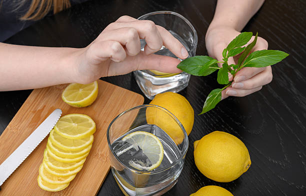 istock A woman prepares drinking water with lemon and mint. 2220393479