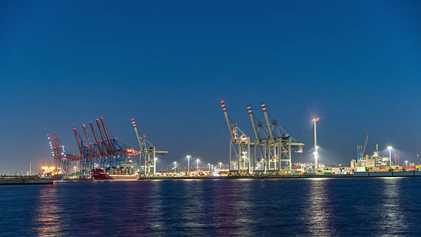 istock Night timelapse of Hamburg cargo port, showcasing container terminals, cranes and cargo ships on the Elbe River. 2220394449