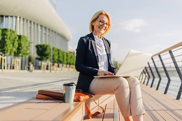 istock Woman Smiling While Working on Laptop by the River 2220396606
