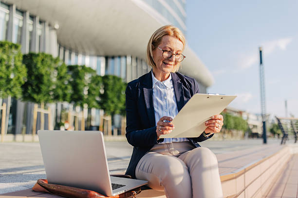 istock Senior woman working outdoors with a laptop and notes 2220396890