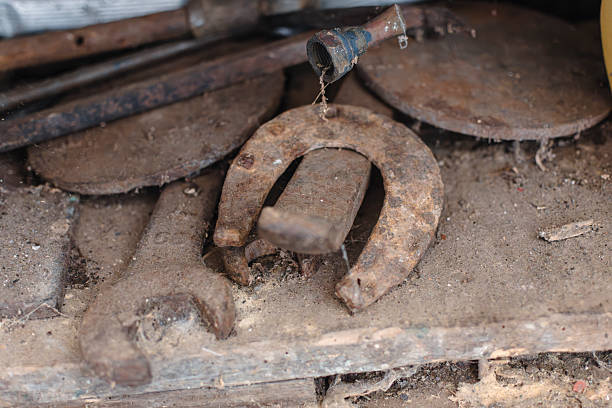 A bunch of old rusty tools and horseshoes are on a table. Scene is nostalgic and somewhat eerie, as the old tools and horseshoes evoke a sense of the past