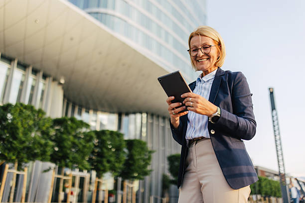istock Happy woman smiling while using tablet outdoors 2220397176