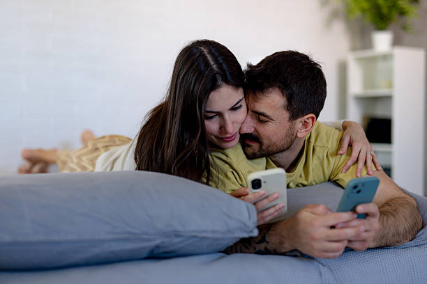 istock Young couple lying in bed and using smartphones 2220399241