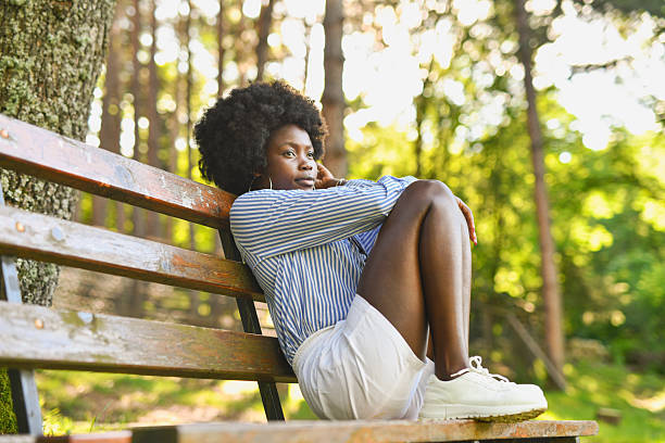 istock Tranquil Female Sitting Still on Park Bench Surrounded by Trees and Gentle Breeze 2220399896