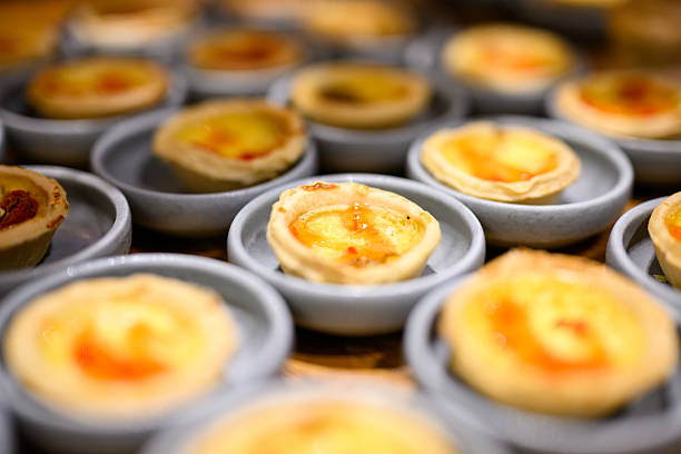 Closeup of golden-brown mini quiches sitting in small grey dishes at a visually appealing buffet.