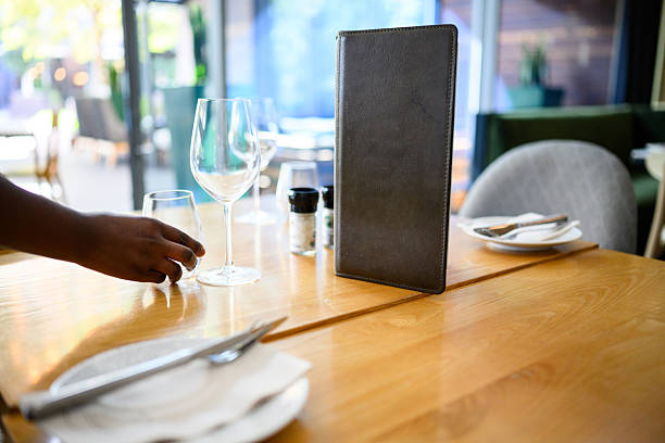 Hand setting an elegant restaurant table for two, placing drinking glasses and plates for a sophisticated dining experience.