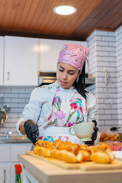 A Latina chef from Bogota, Colombia, between 30 and 34 years old, prepares food for a catering event using her apron to do the preparation.