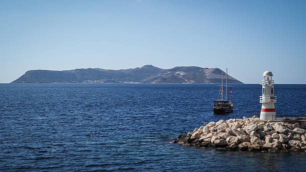 A picturesque panorama featuring boats docked by a calm harbor in southern Turkey, with quaint town architecture and majestic mountains creating a tranquil and inviting atmosphere