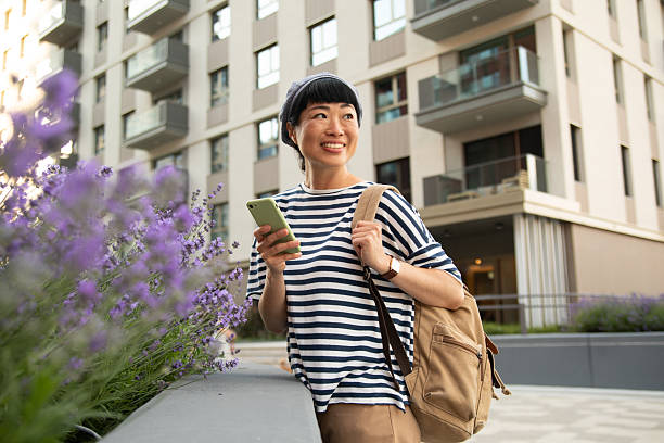 istock Smiling tourist holding smartphone and looking around in urban setting 2220403532
