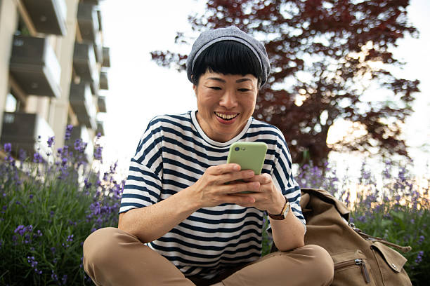 istock Smiling tourist using smartphone while relaxing in a city park 2220403666