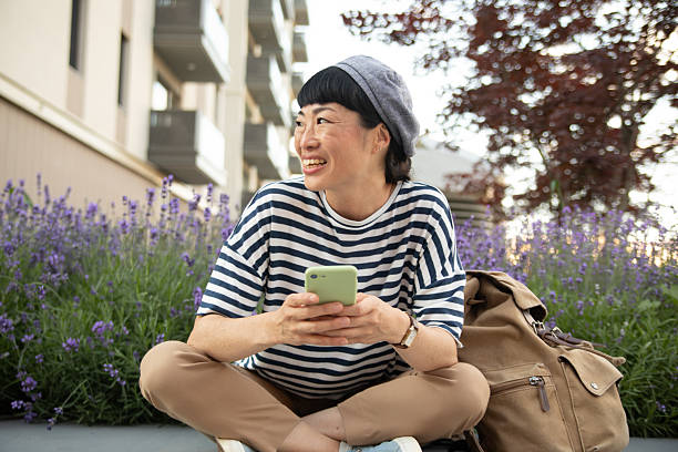 istock Smiling tourist using smartphone while relaxing near lavender flowers 2220403697