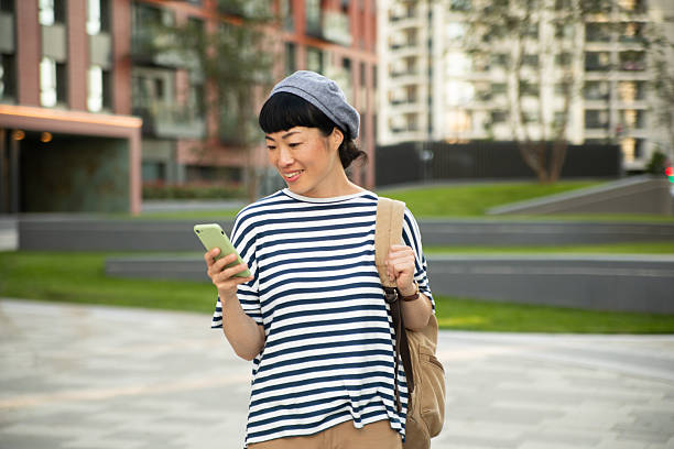 istock Smiling tourist using smartphone while walking in city 2220403750