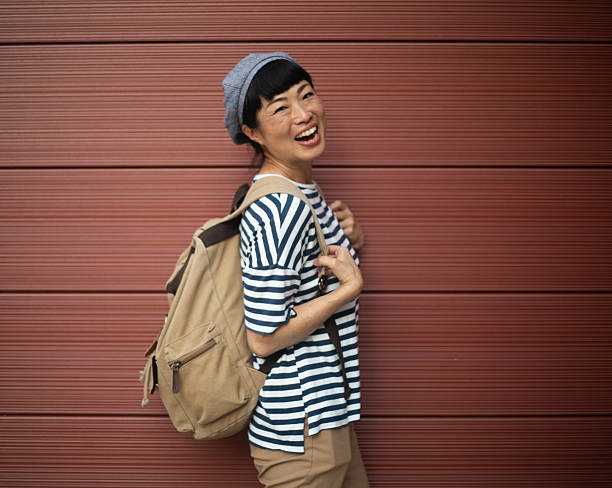 istock Happy tourist smiling with backpack in front of red wall 2220404108